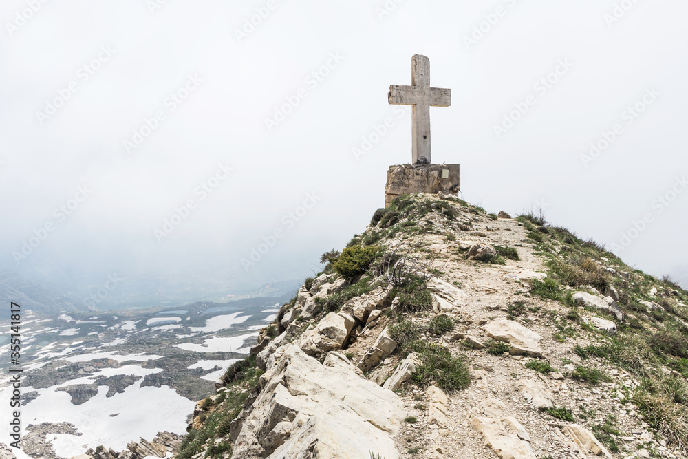 Cross on a cliff overlooking a valley on a cloudy day in Sayidat al Qarn church, Aaqoura, Lebanon