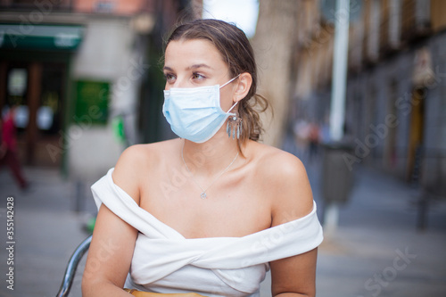 Chica joven con mascarilla en una terraza en la calle photo