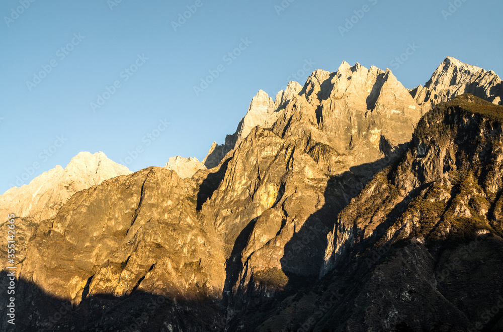 Fototapeta premium Orange jagged mountain peaks of Tiger Leaping Gorge at sunset, Yunnan, China