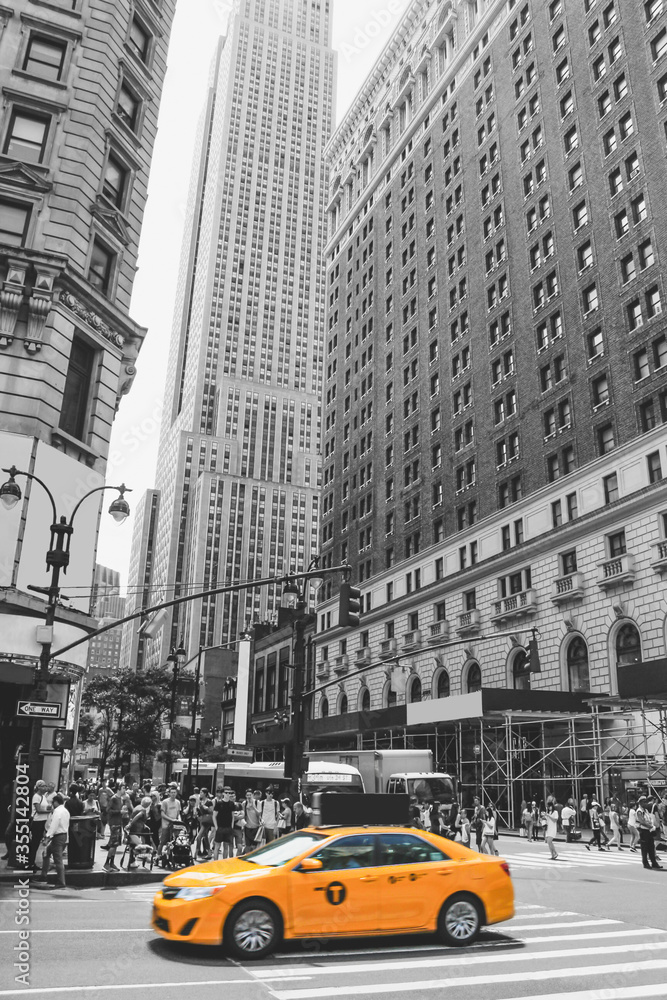 Obraz New York City Taxi, o charakterystycznym żółtym kolorze, przejeżdża przez jedną z najpopularniejszych i najbardziej turystycznych części miasta. Rozmycie ruchu ostrości