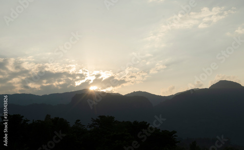 The sunset behind the clouds with dark mountain.sunset nature background.