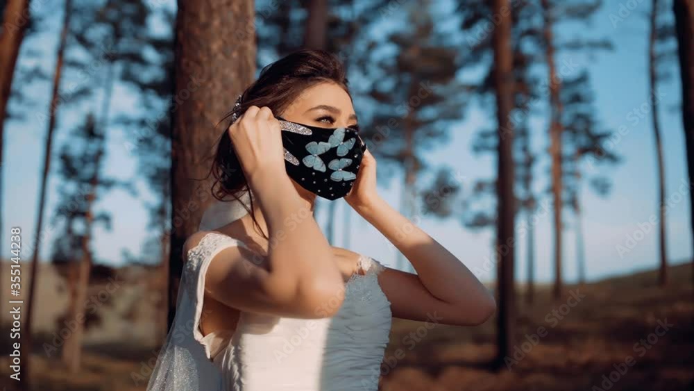 A portrait of a beautiful woman putting a mask on her face. It is a very interesting mask in black and with butterflies sewn on it. A portrait of a beautiful woman putting a mask on her face. It is a very interesting mask in black and with butterflies sewn on it.