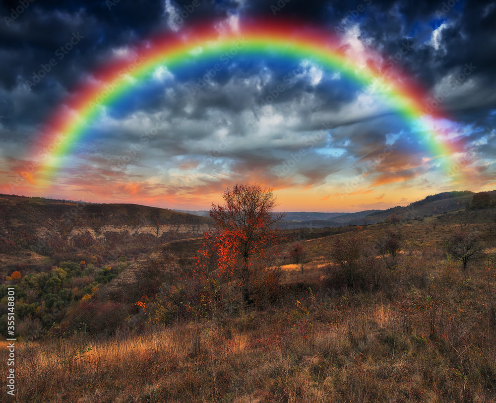 Rainbow with clouds over a rock