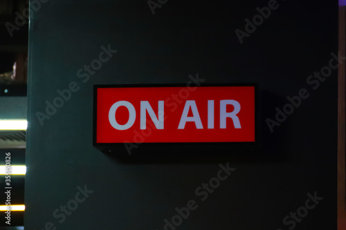 On Air sign icon glowing on the wooden wall of sound recording studios