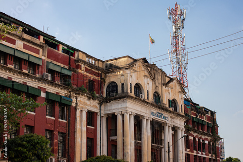 Historical colonial building reconverted into an apartments house. Mobile communications antenna in the building. High columns at the entrance. Yangon - Rangoon, Myanmar - Burma, Southeast Asia photo