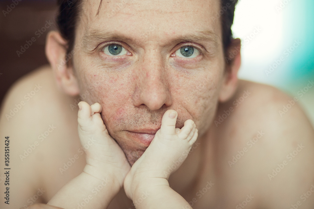 Portrait of the man and newborn baby's small legs on his lips Portrait of the man and newborn baby's small legs on his lips