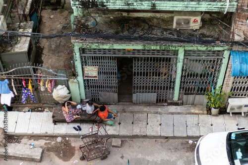 Women delousing their hair. Three women on the street sitting in front of their house, examination for head louse eggs (nits) on the hair. Yangon - Rangoon, Myanmar - Burma, Southeast Asia