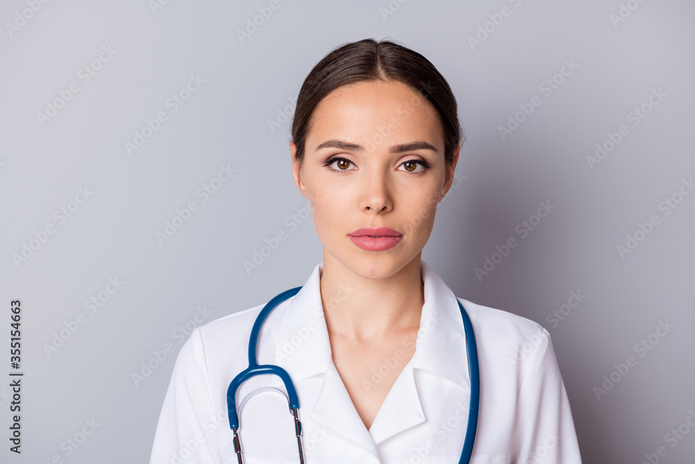 Portrait closeup photo of attractive serious family doctor doc not smiling experienced professional listen patient focused wear medical gown lab coat stethoscope isolated grey background Portrait closeup photo of attractive serious family doctor doc not smiling experienced professional listen patient focused wear medical gown lab coat stethoscope isolated grey background