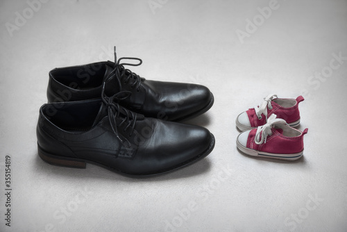 Fotografia Father with daughter concept, baby and adult shoes
