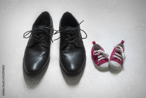 Father with daughter concept, baby and adult shoes 