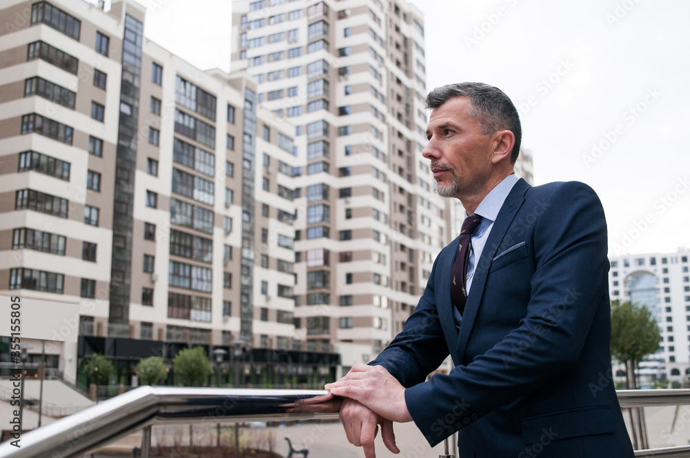 Confident and successful. Handsome young businessman adjusting his jacket and looking away while walking outdoors with office building in the background Confident and successful. Handsome young businessman adjusting his jacket and looking away while walking outdoors with office building in the background