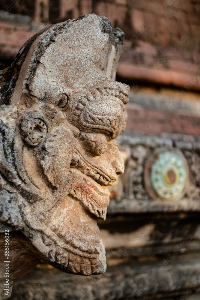 Stone face. Close up detail of a sculpture attached to the facade of a buddhist temple. Bagan, Myanmar - Burma, Southeast Asia