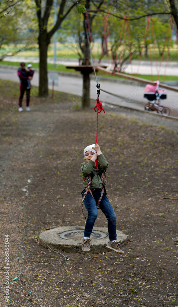 Fototapeta premium Brave little boy walking on a rope bridge