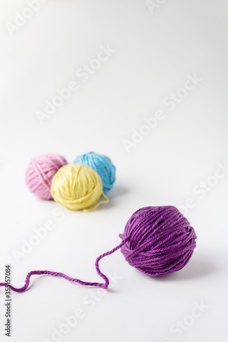 Close up of violet woolen ball. Three other woolen balls in background on light backdrop.