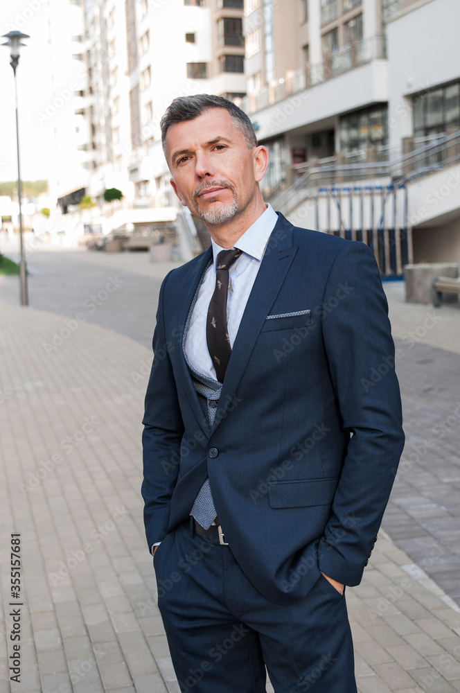 Attractive middle-aged businessman with a friendly smile looking directly at the camera, head and shoulders in the office