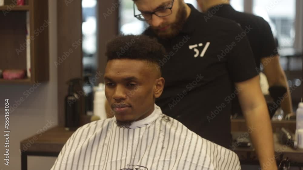 Vidéo Stock Young attractive european professional barber making a new modern haircut for