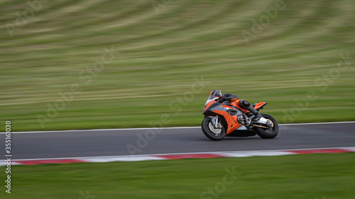 A panning shot of an orange racing bike cornering on a track © SnapstitchPhoto
