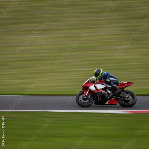 A panning shot of a red and white racing bike cornering on a track