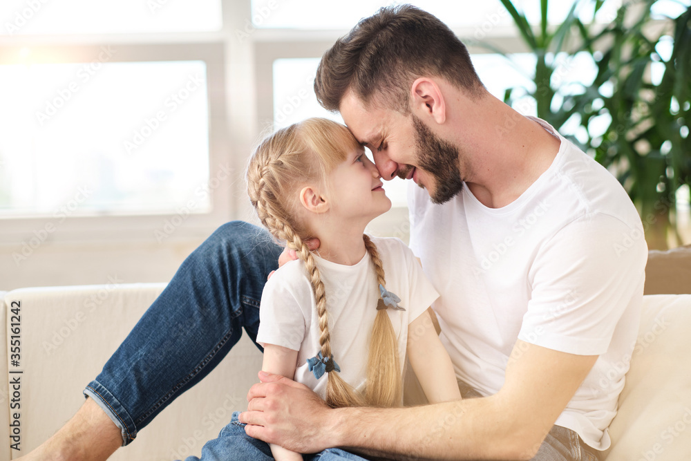 A loving father clung to his cute little daughter, face to face, loves children. Family unity and tranquility. A girl with blond hair is smiling. Father and family day concept. A loving father clung to his cute little daughter, face to face, loves children. Family unity and tranquility. A girl with blond hair is smiling. Father and family day concept.