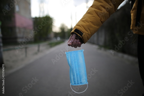 A man holds a medical mask in his hand. Medical concept. A man holds a face mask on the street. Virus stop 