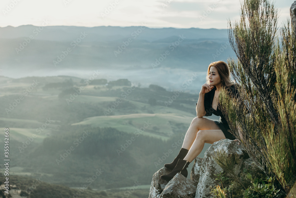 Beautiful asian woman sit and posing at the top of The Organ Pipes , Mt cargill Dunedin New Zealand.