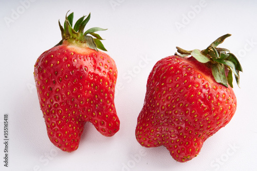 Trendy ugly strawberries on a light background photo