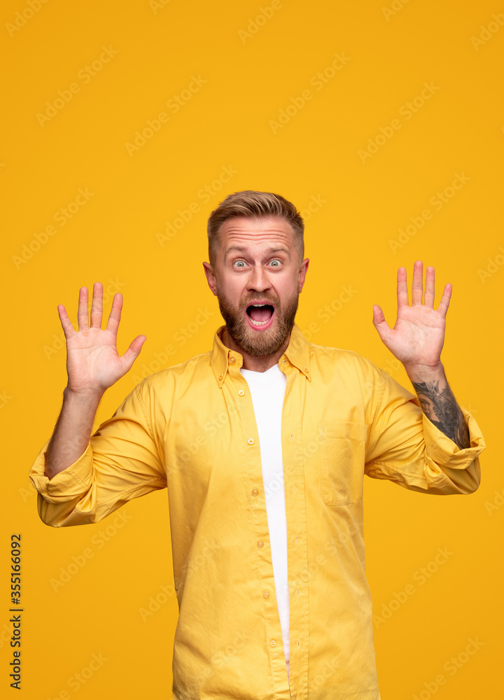 Surprised adult man with hands raised screaming in light studio Surprised adult man with hands raised screaming in light studio