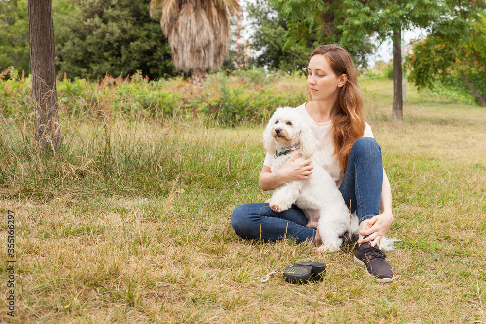 Fototapeta premium Beautiful young girl on a walk in the Park with her dog.