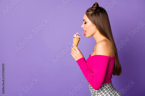 Profile photo of pretty lady two cute pretty buns stick tongue out mouth eat vanilla ice cream wear pink off-shoulders cropped top skirt isolated pastel purple color background