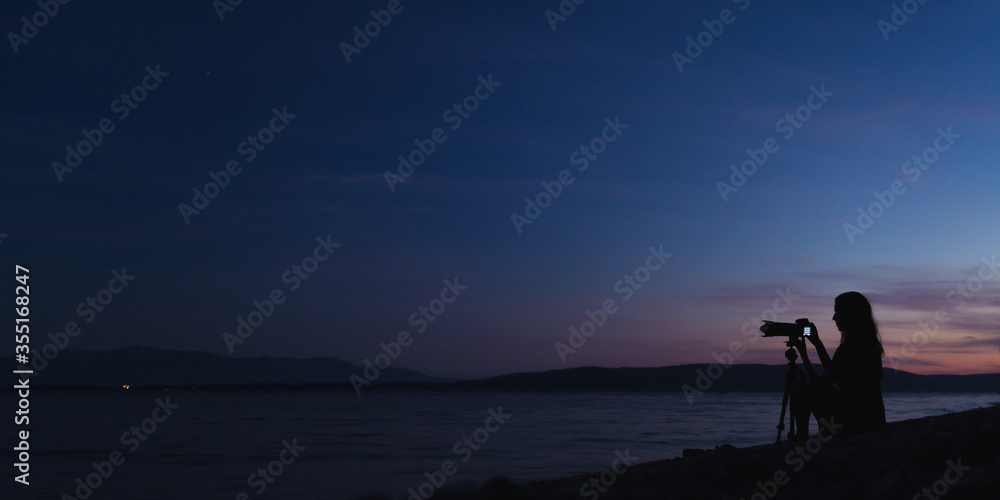 Female photographer taking photos on the beach at dusk