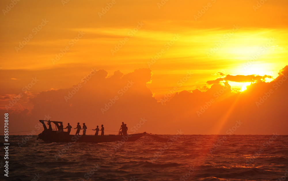 The fisherman boat pull out the net on the ocean during sunset time The fisherman boat pull out the net on the ocean during sunset time