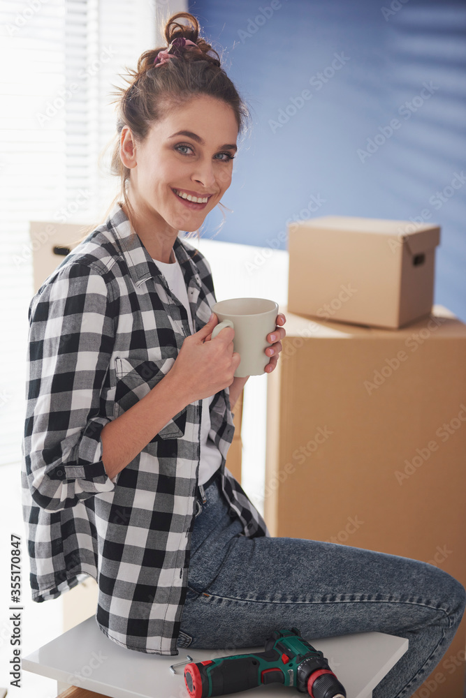 Vertical image of woman having coffee break while moving house Vertical image of woman having coffee break while moving house