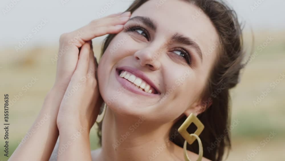 Woman leaned on hands, looking at the sky and smiling light at windy nature Woman leaned on hands, looking at the sky and smiling light at windy nature