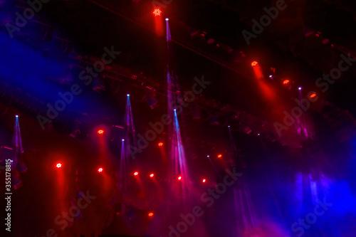 Stage lights. Several projectors in the dark. Multi-colored light beams from the stage spotlights on the stage in the smoke at the time of the entertainment show. Night club. Lights show. Lazer show