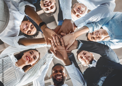 Happy Coworkers Holding Hands During Teambuilding Meeting Standing In Office photo