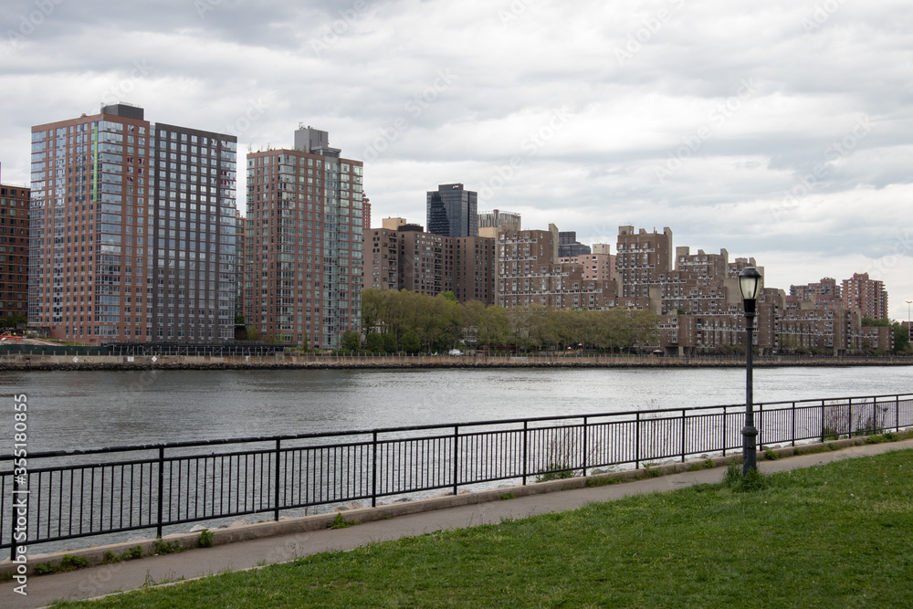 Queensbridge Park with a Street Light along the East River with the Roosevelt Island Skyline in New York City	