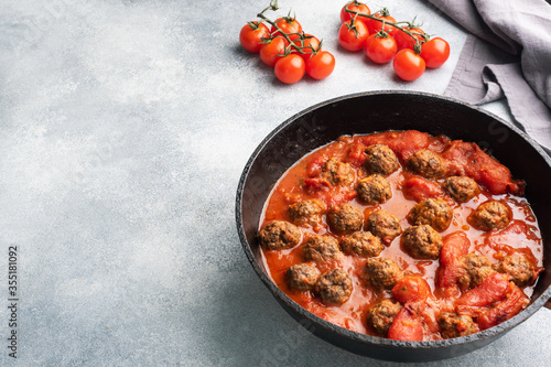 Delicious juicy Meatballs in tomato sauce are cooked in a castiron pan. Concrete background. Copy space.