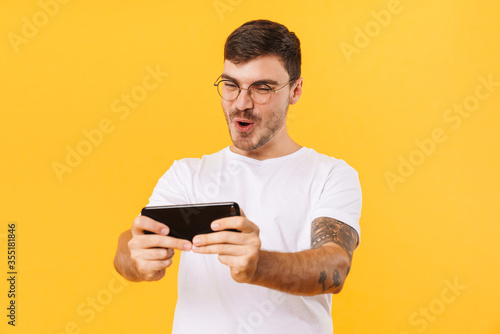 Photo of excited bristle man playing video game on cellphone