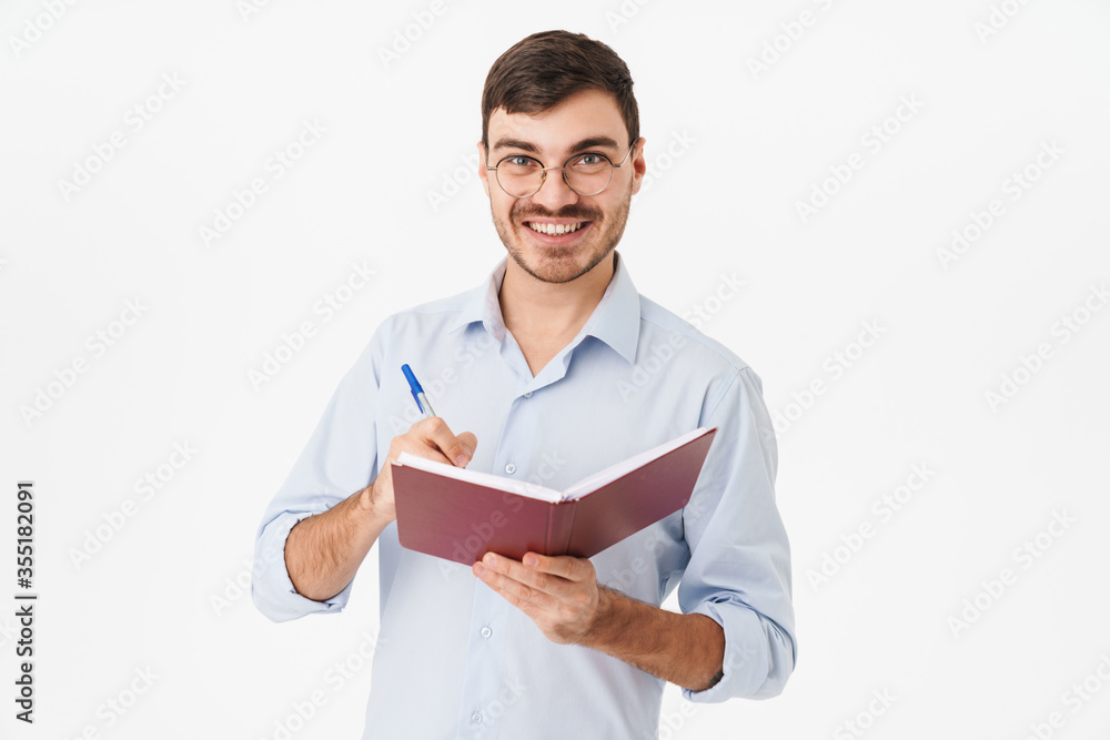 Photo of smiling handsome man in eyeglasses making notes in diary Photo of smiling handsome man in eyeglasses making notes in diary