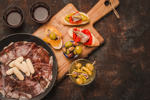 Spanish tapas with jamón ibérico or cured ham, olives, anchovies, wine. Typical spanish appetizers copy space. 