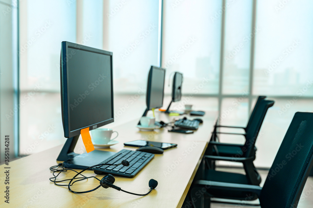 Customer support representative talking on headset while using computer. Businessman working at desk with colleague in background. He is wearing casuals in call center. Customer support representative talking on headset while using computer. Businessman working at desk with colleague in background. He is wearing casuals in call center.
