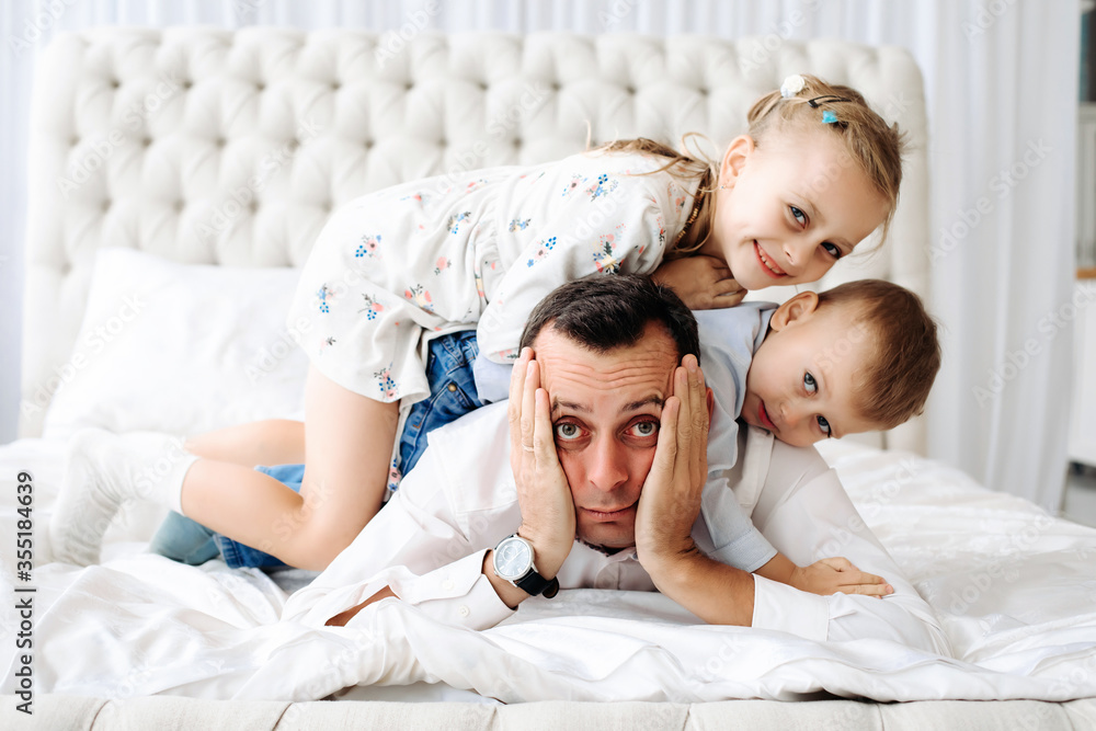 The image of a person left at home alone with children. Daughter and son climb on the father. The image of a person left at home alone with children. Daughter and son climb on the father.