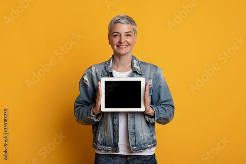 Digital Tablet With Blank Black Screen In Hands Of Smiling Mature Woman