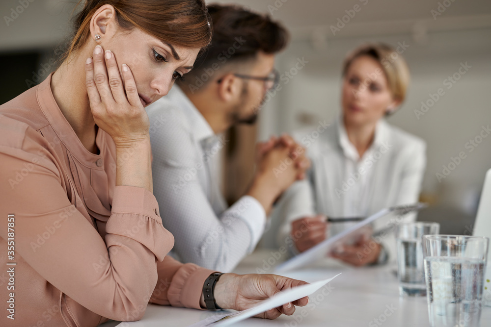 Young woman analyzing blueprints while being on a meeting with real estate agent with her husband. Young woman analyzing blueprints while being on a meeting with real estate agent with her husband.
