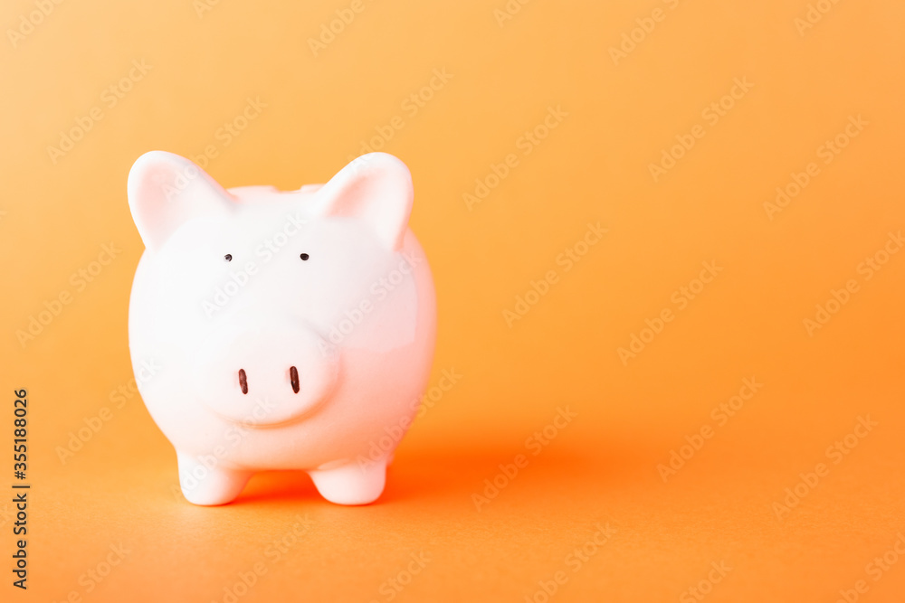 Front small white fat piggy bank, studio shot isolated on orange background and copy space for use, Finance, deposit saving money concept Front small white fat piggy bank, studio shot isolated on orange background and copy space for use, Finance, deposit saving money concept
