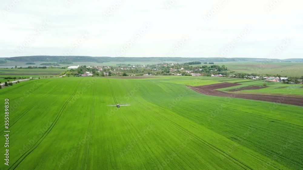 Aerial view of farming tractor spraying on field with sprayer, herbicides and pesticides Aerial view of farming tractor spraying on field with sprayer, herbicides and pesticides