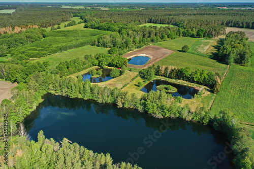 Aerial view of a large rectangular pond in front of smaller ponds in a flat landscape with small tree islands between meadows