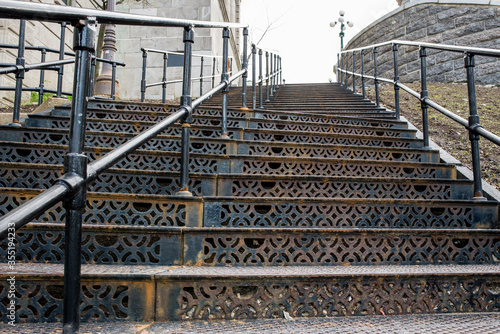 Frame-filling view of intricate ironwork scrolled stairs and iron handrail in Quebec, Canada.