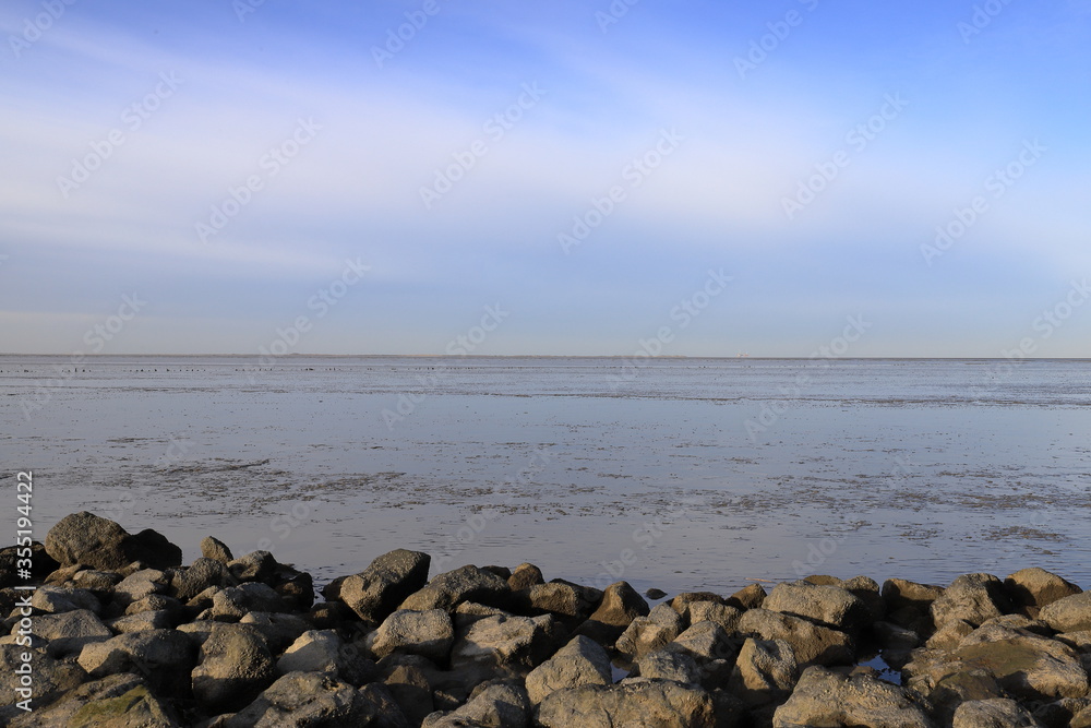Beautiful sky over the sea at low tide. Photo was taken from the shoreline with rocks. Beautiful sky over the sea at low tide. Photo was taken from the shoreline with rocks.