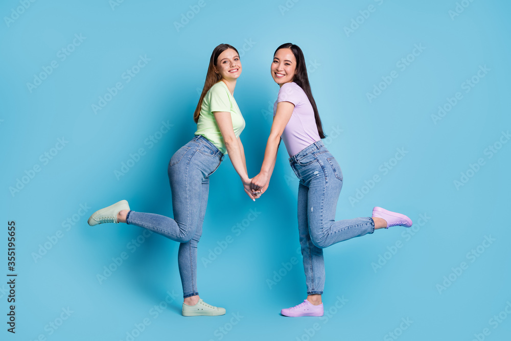Full body profile photo of two affectionate lesbians couple young students  fellowship buddies hold arms wear casual t-shirts jeans footwear isolated  blue color background Stock Photo | Adobe Stock